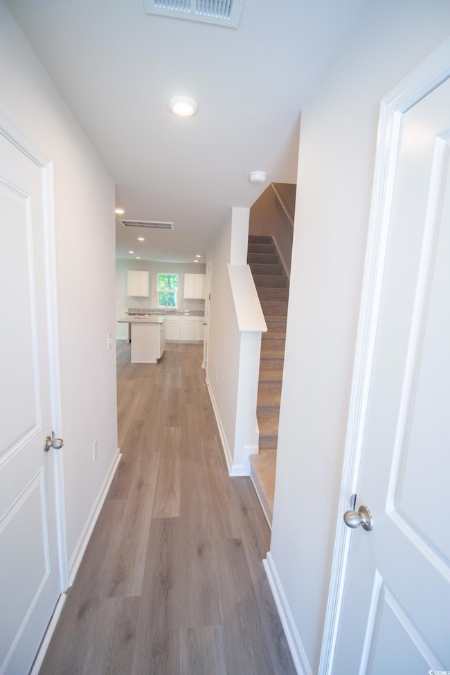 Corridor featuring light wood-type flooring, stairway, recessed lighting, and baseboards