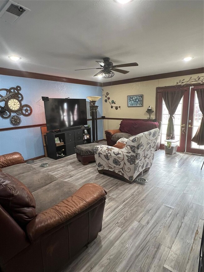 Living room with a ceiling fan, visible vents, woo