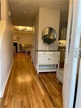 Hallway featuring wood-type flooring, a textured ceiling, and baseboards