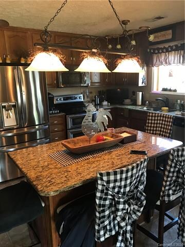 Kitchen with granite counter tops, stainless steal appliances and large island bar.