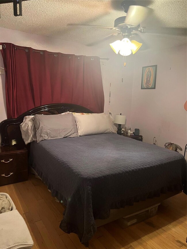 Bedroom with ceiling fan, a textured ceiling, and 
