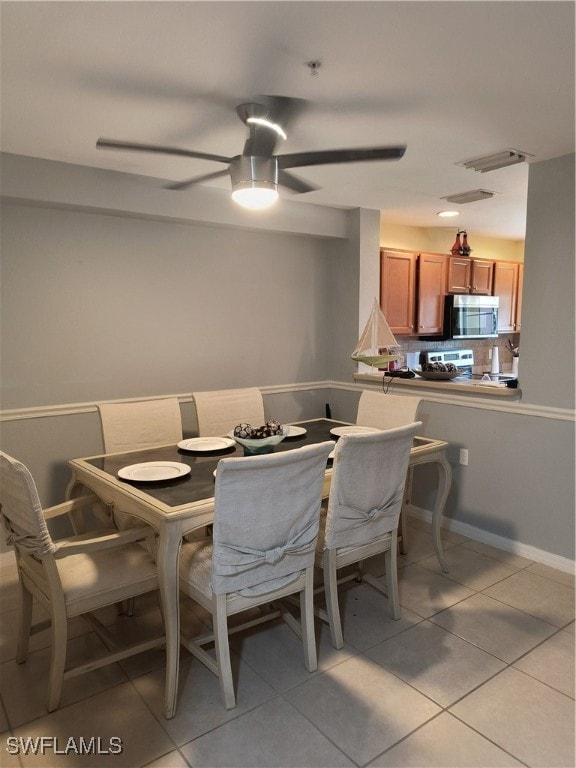 Dining room featuring a ceiling fan and light tile