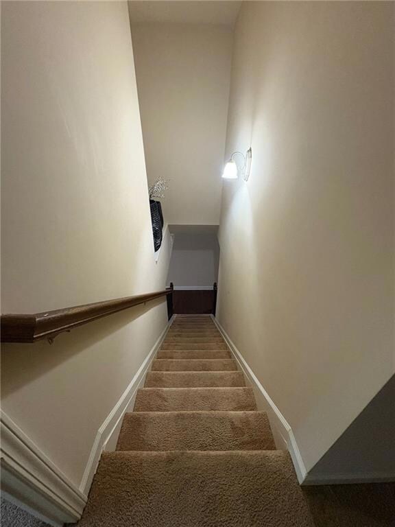 Staircase featuring baseboards and carpet flooring