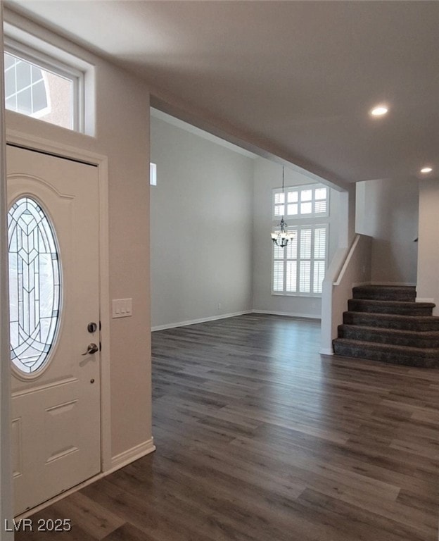 Foyer entrance with a chandelier, stairs, dark woo