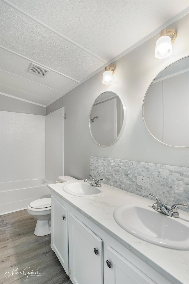 Full bathroom featuring vanity, backsplash, toilet