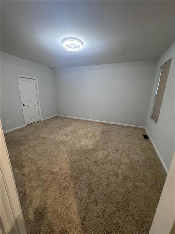 Unfurnished room featuring light colored carpet and baseboards