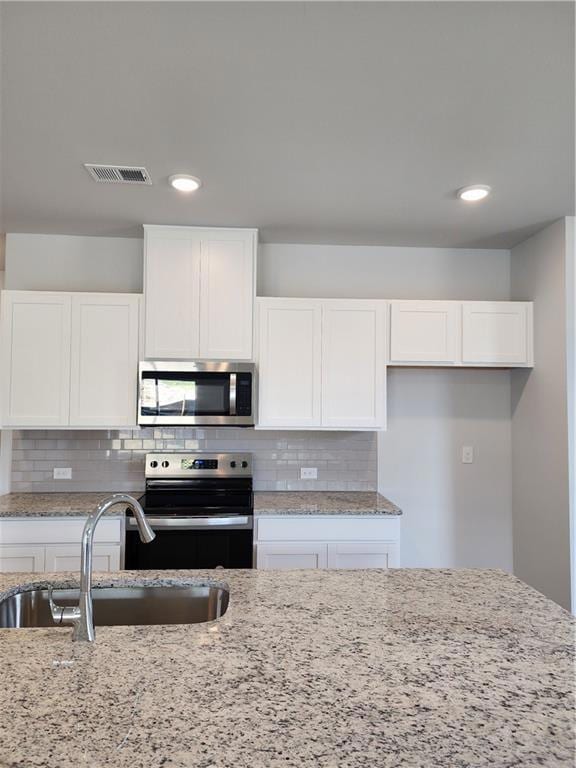 Kitchen featuring white cabinetry, visible vents, 