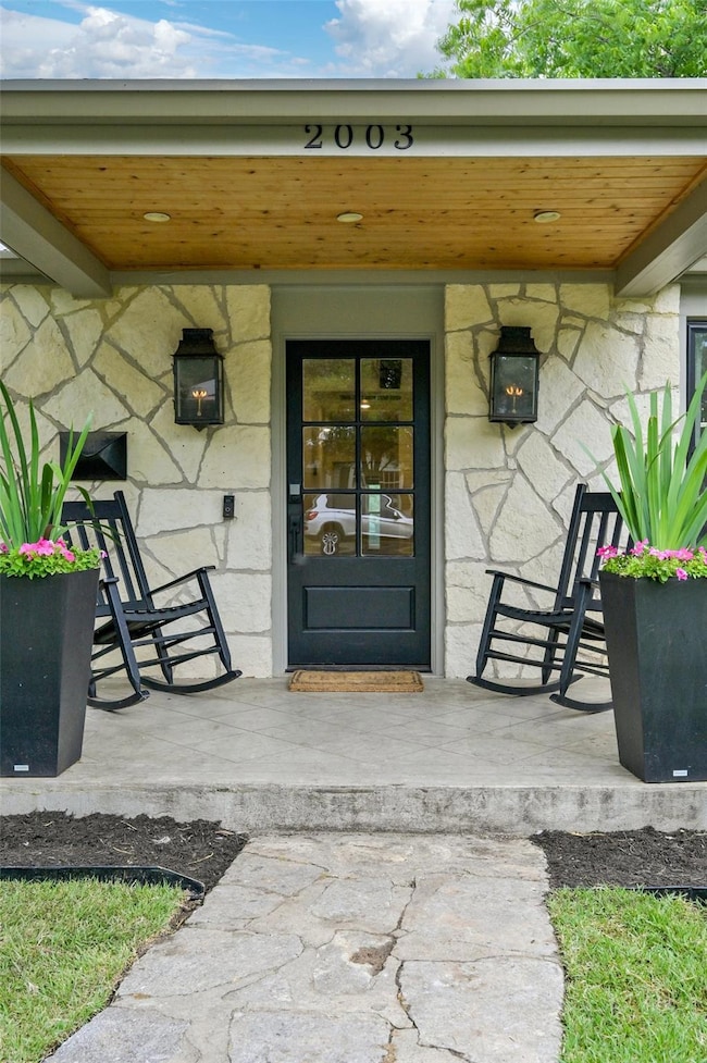 Property entrance featuring a porch and stone sid
