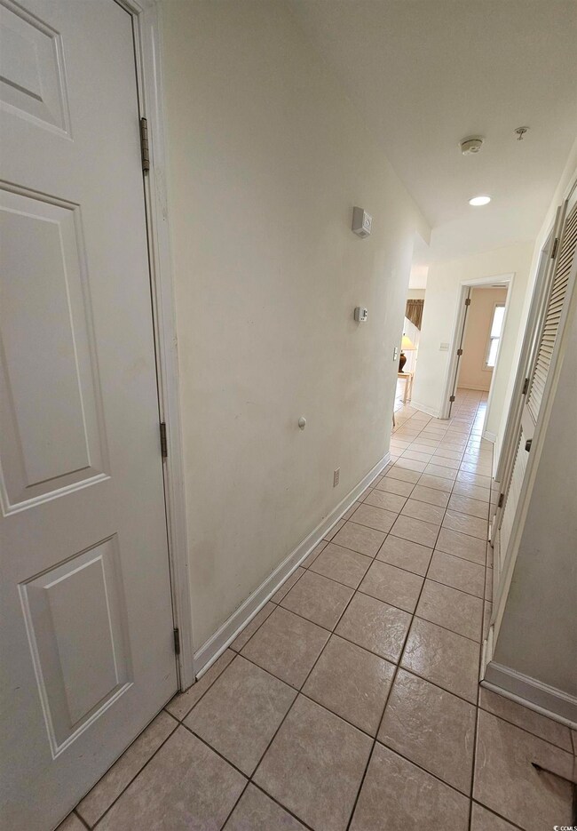 Hallway featuring light tile patterned floors and baseboards