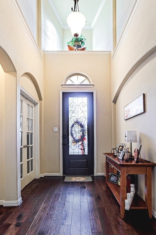 Entryway featuring a high ceiling, dark wood finished floors, french doors, arched walkways, and ornamental molding