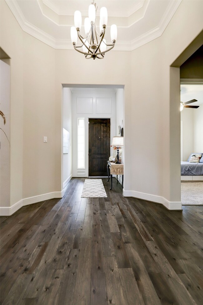 This is a look down the long main hallway, to your front door! Palatial, structural nuances are plentiful, including the rich wood floor, pale earth tones on the walls, with classic crown molding and sophisticated domed tray ceiling . . . for starters!