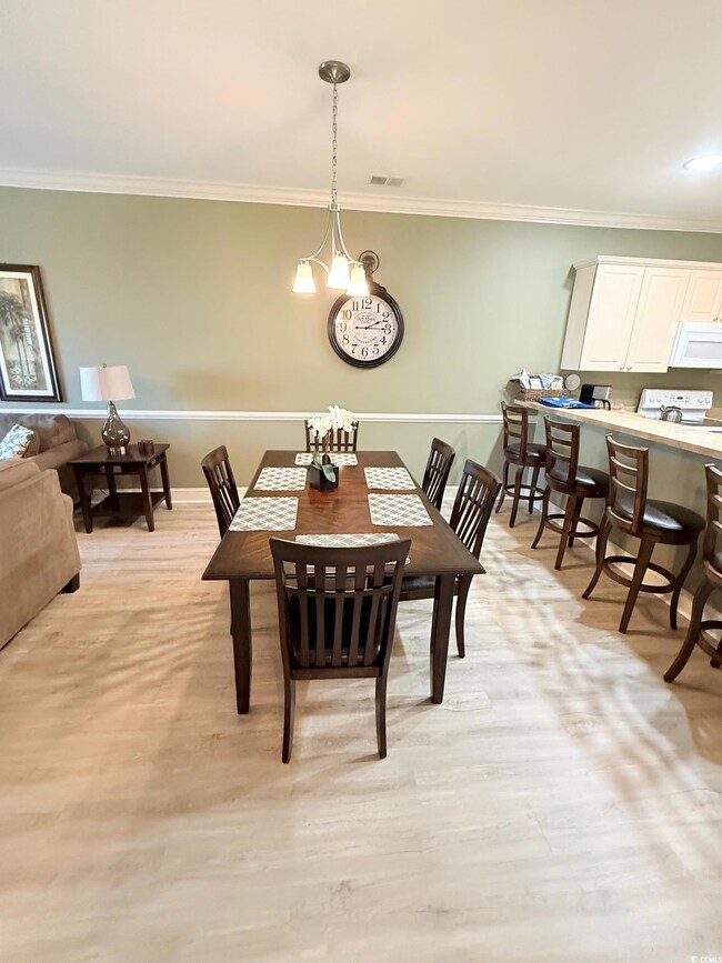 Dining area featuring crown molding and light wood finished floors