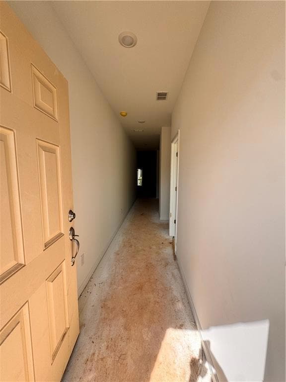Corridor featuring concrete flooring and baseboards
