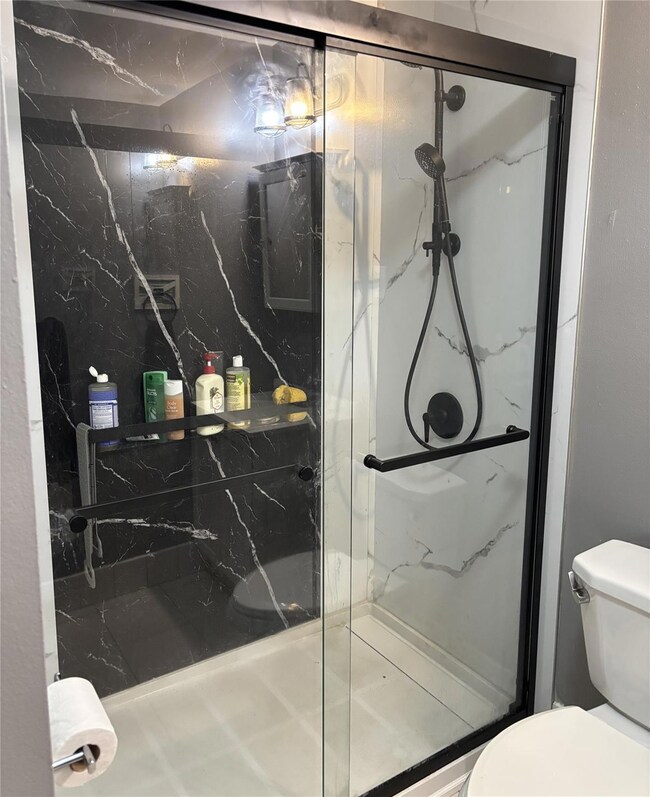 Bathroom featuring toilet and a marble finish shower