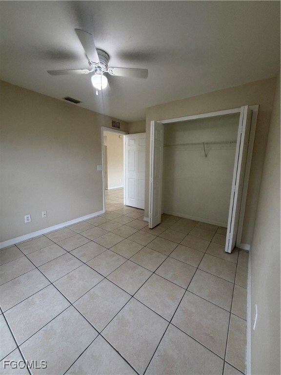 Unfurnished bedroom with light tile patterned floors, a ceiling fan, and a closet
