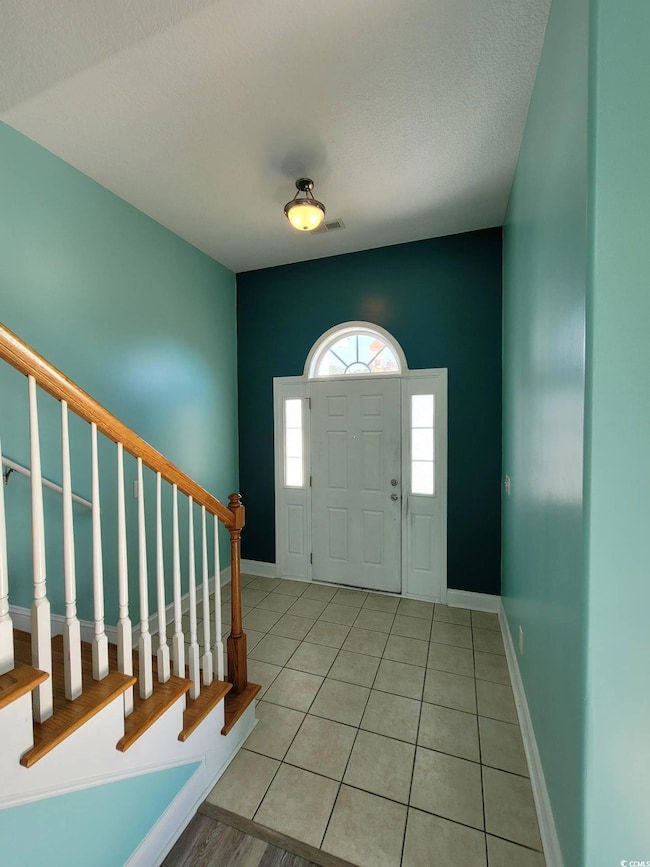 Foyer with light tile patterned floors and stairway
