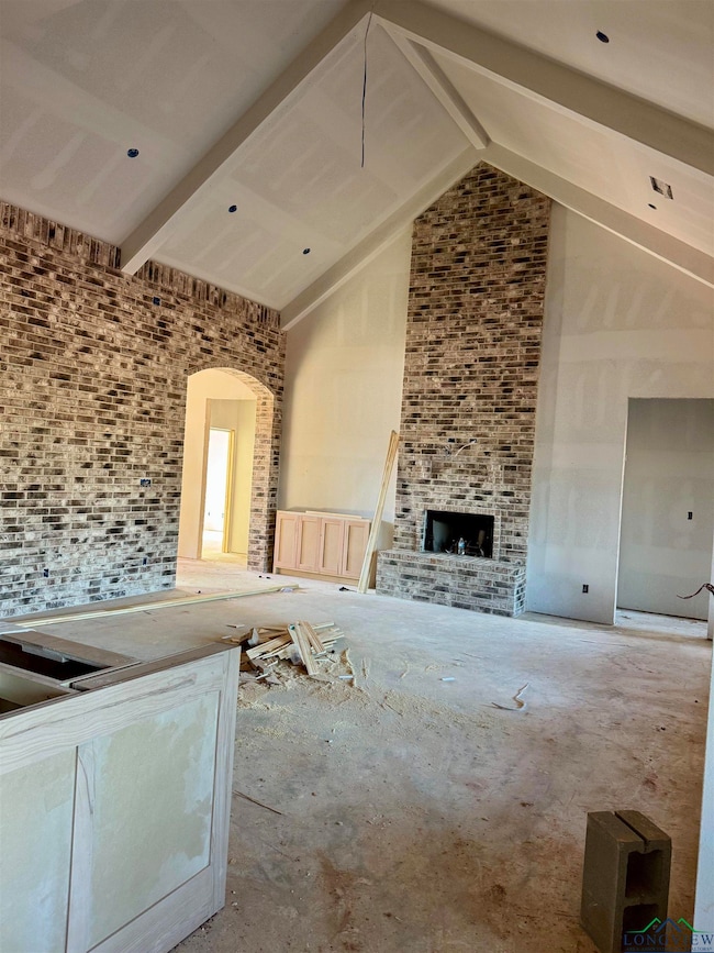Unfurnished living room with beam ceiling and high vaulted ceiling