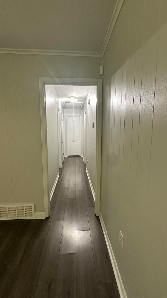 Hall featuring attic access, dark wood-style floors, and crown molding