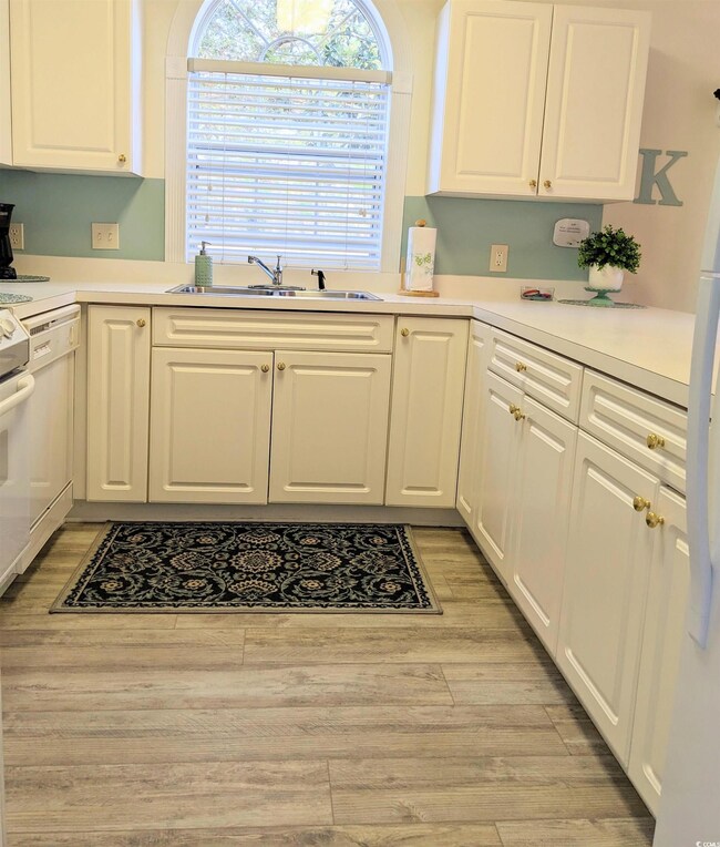 Kitchen with sink, white appliances, light hardwoo
