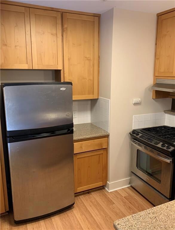 Kitchen featuring tasteful backsplash, light wood