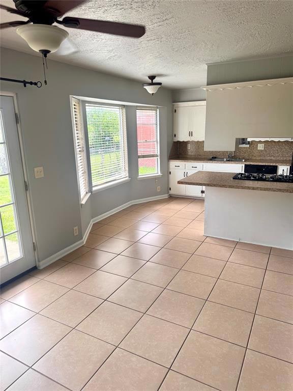 Kitchen with white cabinetry, ceiling fan, backspl