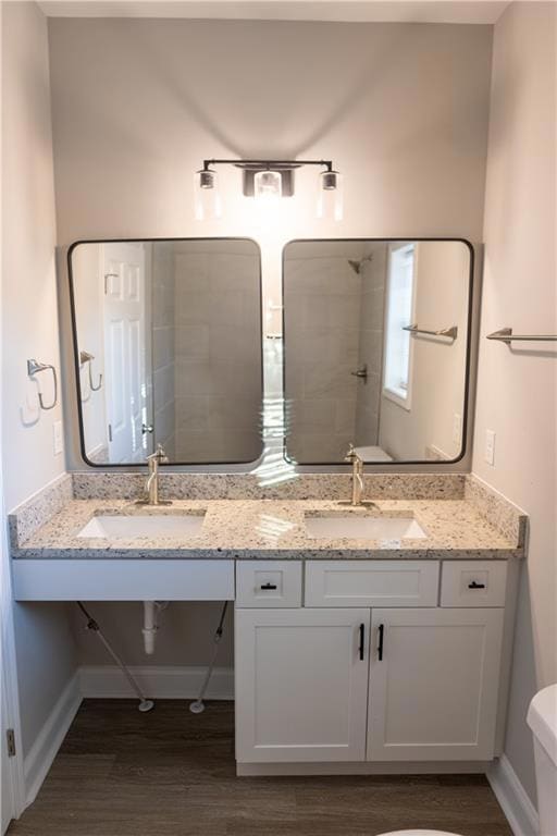 Bathroom featuring baseboards, a sink, and wood fi