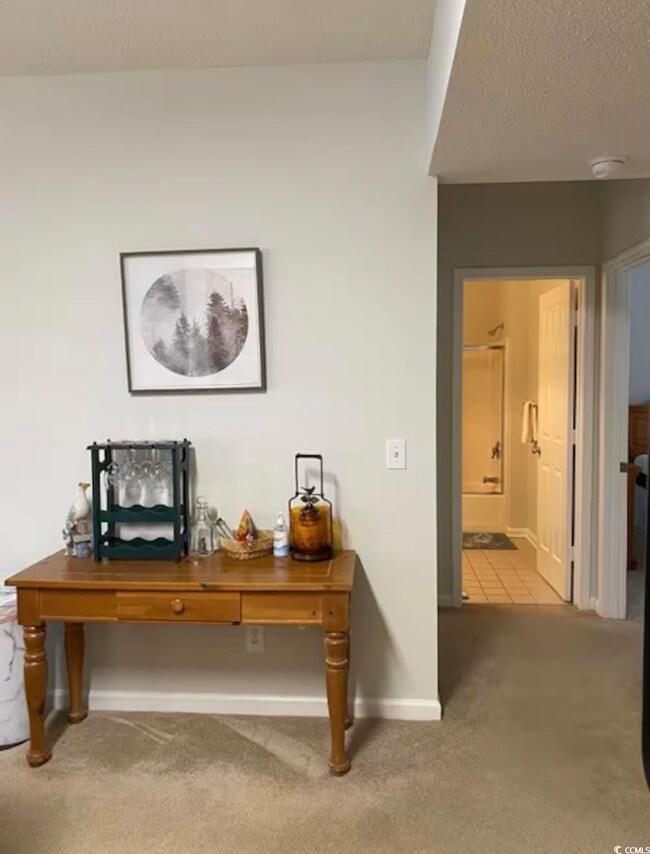 Hall with carpet, baseboards, and a textured ceili