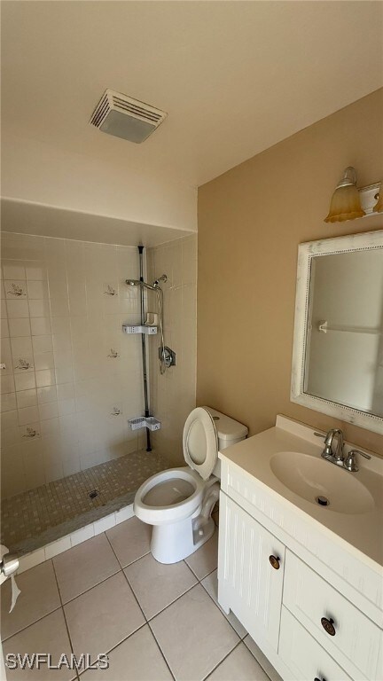 Bathroom featuring a tile shower, tile patterned flooring, vanity, and toilet