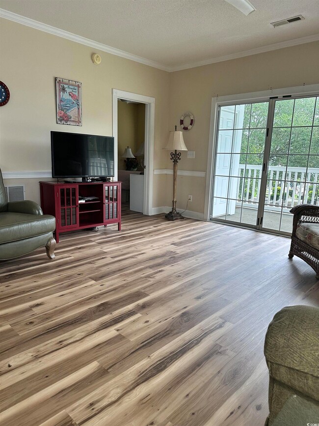 Living area with wood finished floors, crown molding, and a textured ceiling