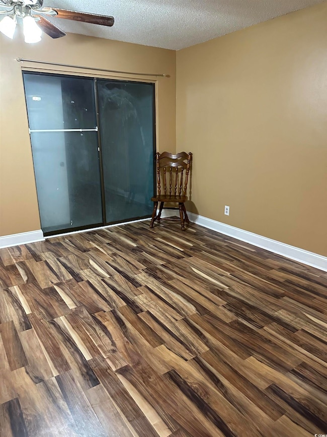 Unfurnished bedroom featuring dark wood-style floors, a textured ceiling, a closet, and ceiling fan