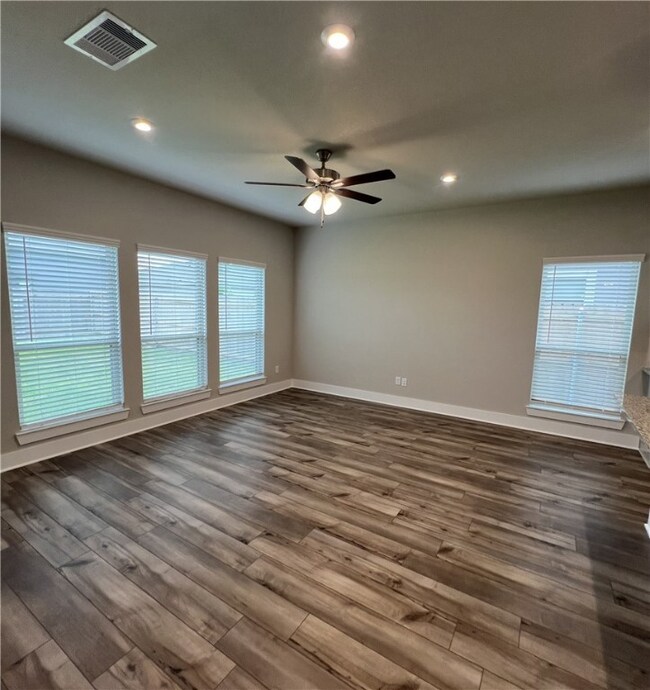 Empty room featuring ceiling fan, dark wood-style