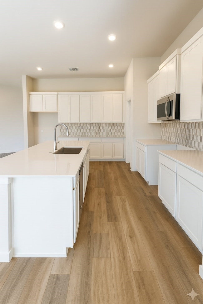 Gourmet kitchen with bright white cabinetry, quartz countertops, stylish tile backsplash, and a huge island perfect for entertaining
