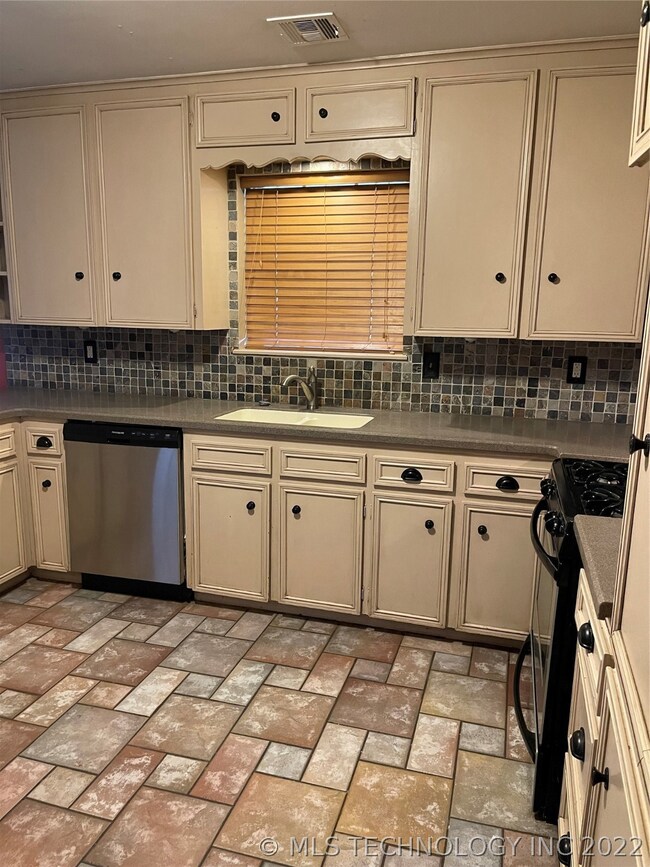 Another view of stainless dishwasher, sink and bac