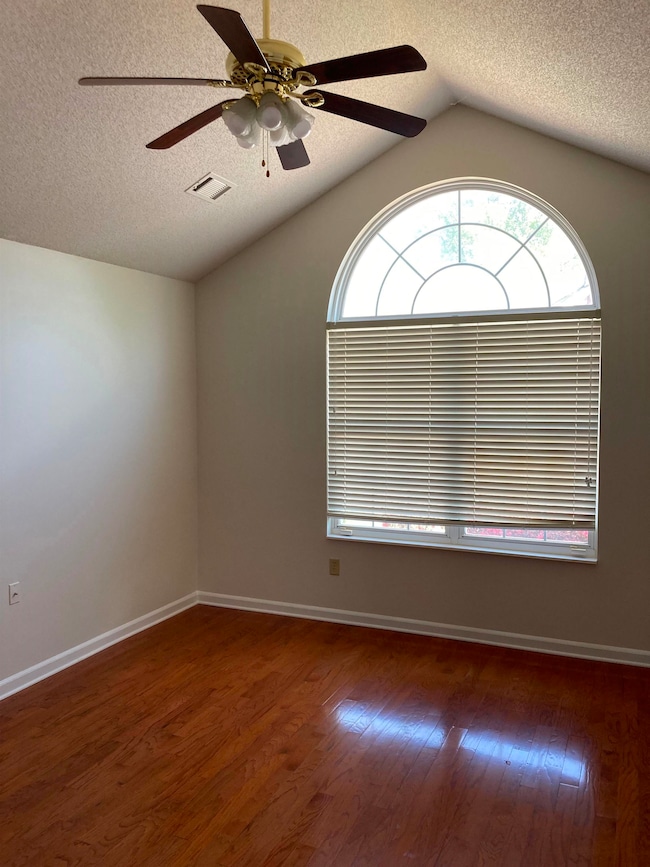 Unfurnished room featuring ceiling fan, vaulted ce