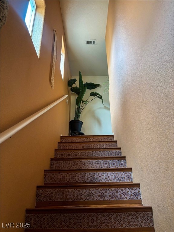 Staircase featuring visible vents and a textured w
