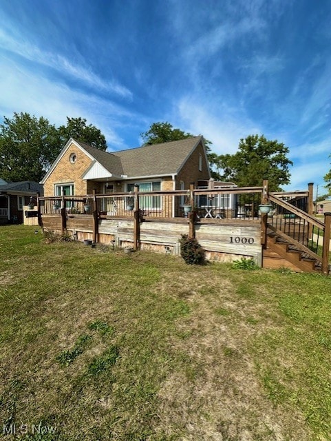 Back of property featuring a wooden deck, a yard, and stairway