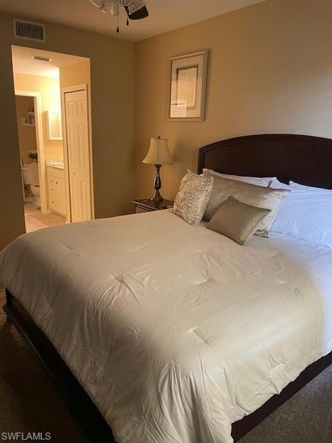 Carpeted bedroom with ensuite bath and visible ven