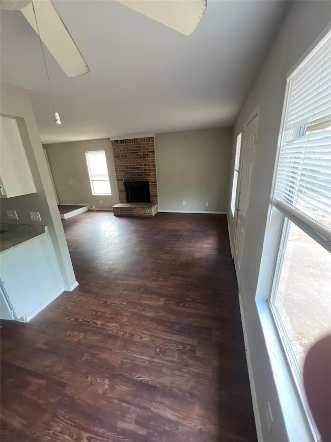 Unfurnished living room featuring dark wood-style flooring and a fireplace