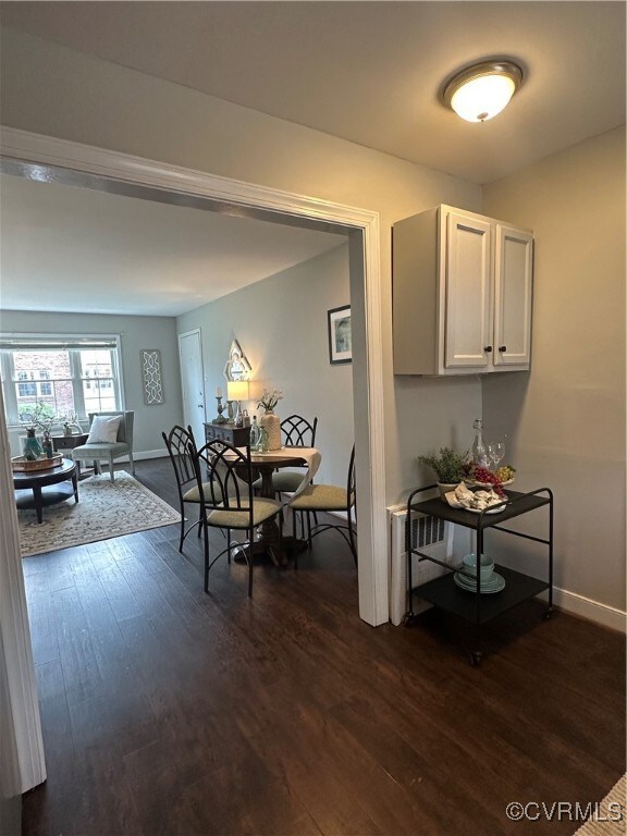 Dining room with dark wood-type flooring and baseb
