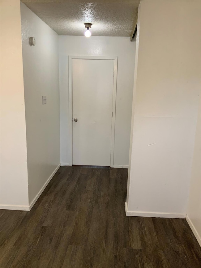 Corridor featuring baseboards, dark wood-type floo