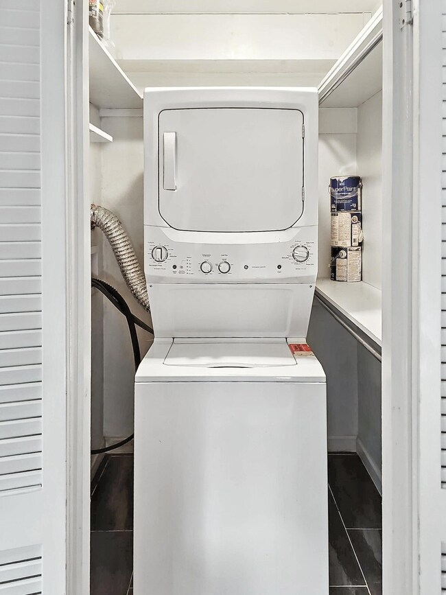 Laundry area featuring stacked washer and clothes dryer and dark tile patterned floors