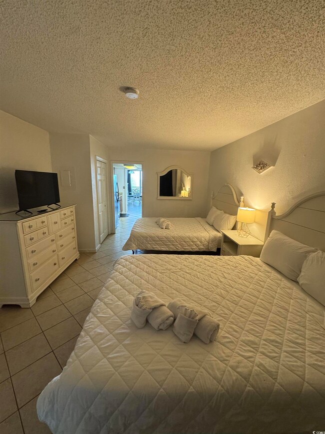 Tiled bedroom with a textured ceiling and baseboar