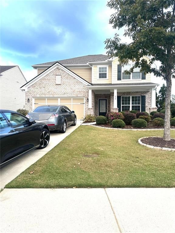 View of front of home with driveway, a front yard, covered porch, an attached garage, and brick siding