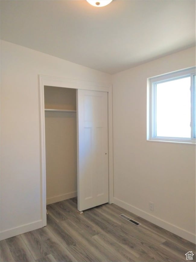 Unfurnished bedroom with dark wood-type flooring and a closet