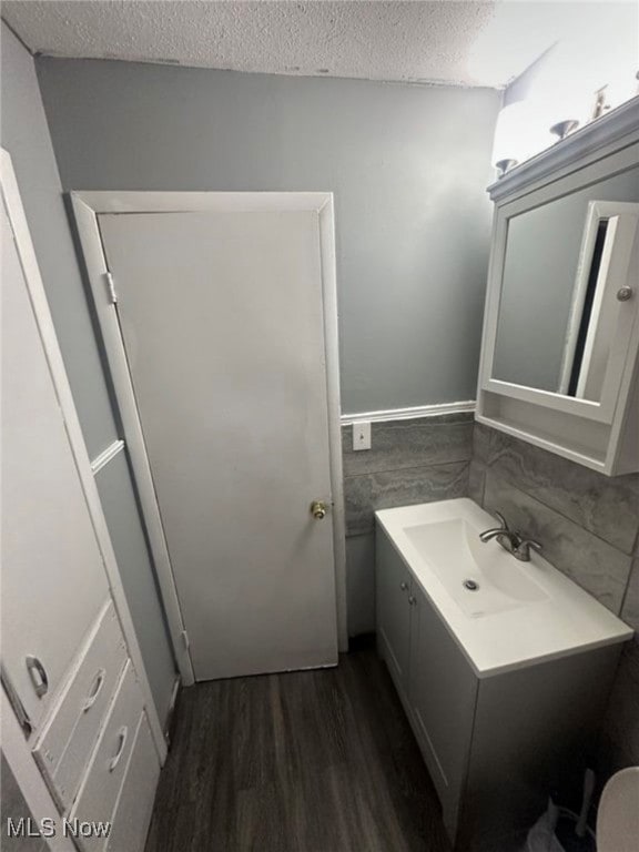 Bathroom featuring vanity, a textured ceiling, dark wood-style floors, and tile walls