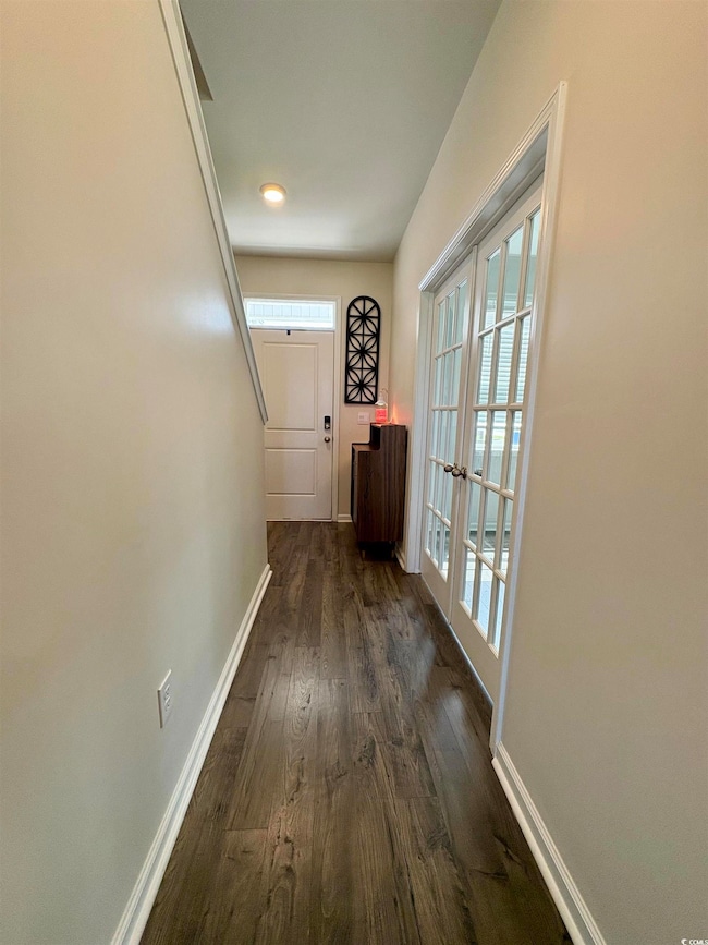 Hallway featuring dark wood-style floors, healthy amount of natural light, and french doors