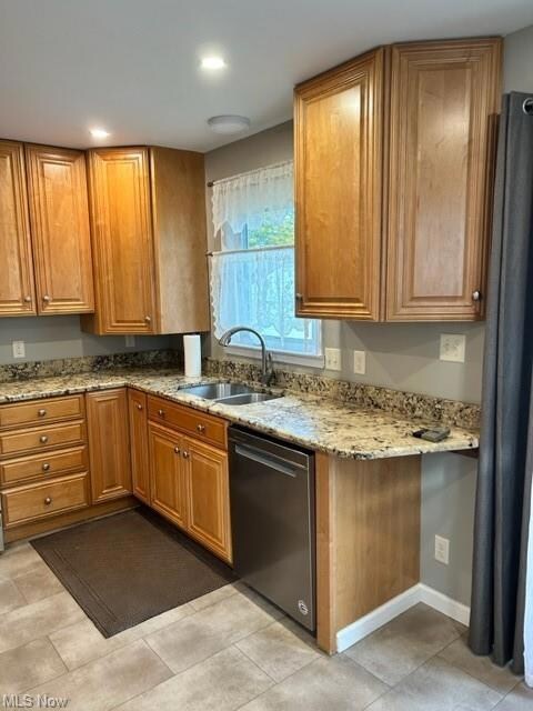 Kitchen with sink, light stone countertops, dishwasher, and light tile floors