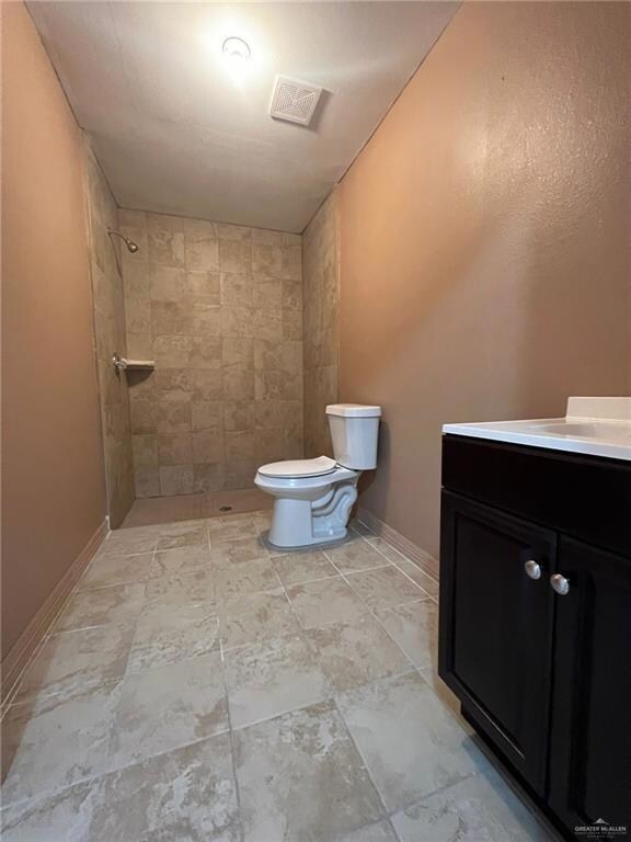 Bathroom with a tile shower, vanity, and toilet