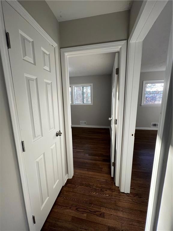 Hallway with plenty of natural light, dark wood-style floors, and baseboards