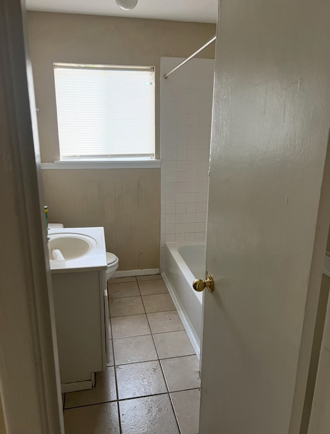Full bath with vanity, light tile patterned floors, and tub / shower combination